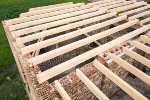 Close up of a brick house with wooden ceiling frame under construction.