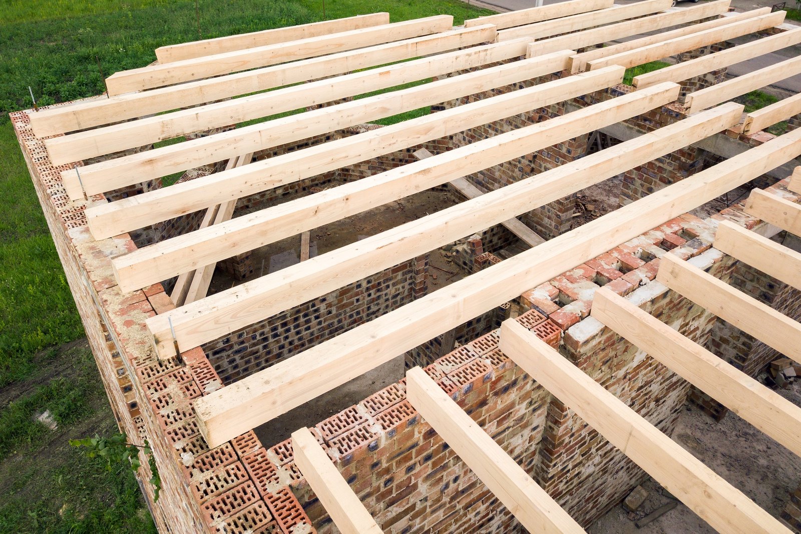 Close up of a brick house with wooden ceiling frame under construction.