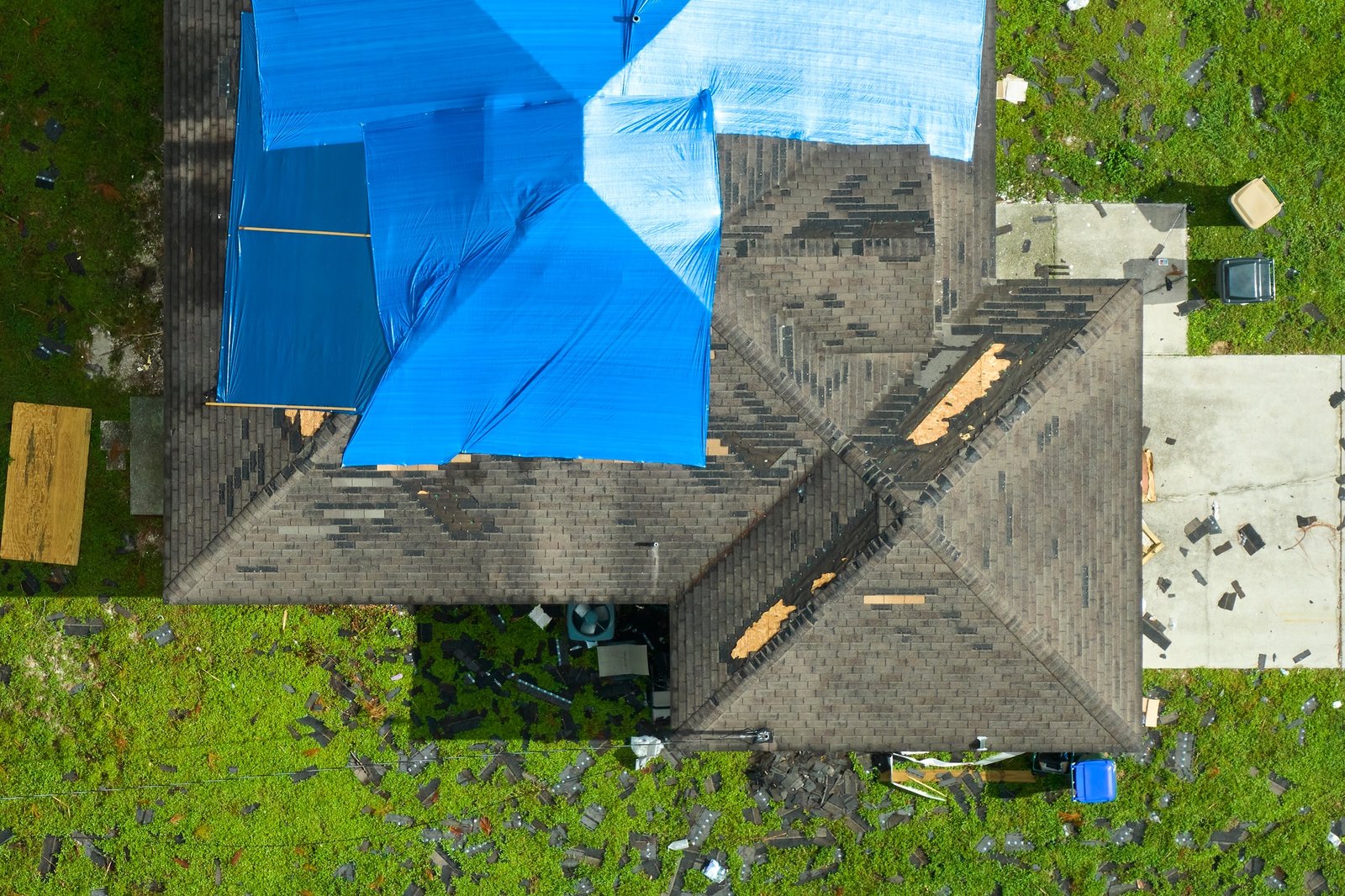 Top view of leaking house roof covered with protective tarp sheets against rain water